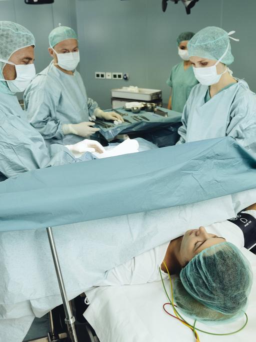 Ein Team operiert eine Frau auf einem Operationstisch.