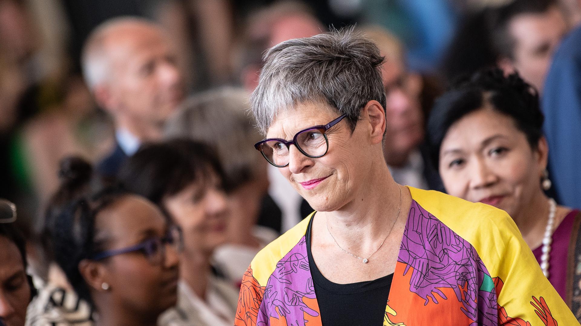 Sabine Schormann, Generaldirektorin der documenta und des Museums Fridericianum, bei der Eröffnung der Documenta Fifteen. Sie trägt kurze Haare, eine markante Brille und bunte Kleidung. Im Hintergrund sind Besucher der Veranstaltung.
Sabine Schormann, Generaldirektorin der documenta und des Museums Fridericianum, bei der Eröffnung der Documenta Fifteen. Sie trägt kurze Haare, eine markante Brille und bunte Kleidung. Im Hintergrund sind Besucher der Veranstaltung.