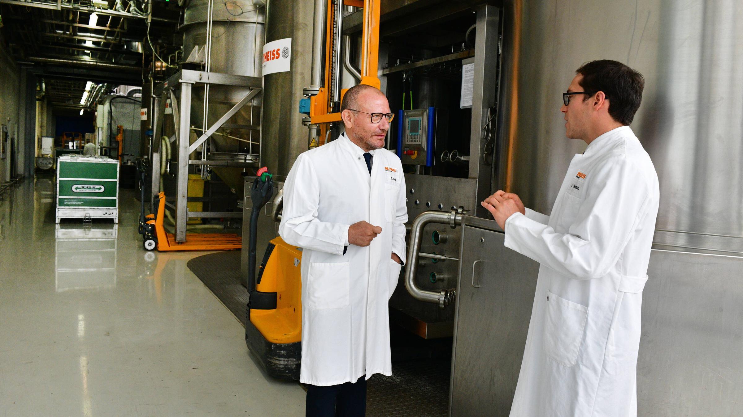 Giuseppe Nardi und Jonas Thielmann \(v.l.\) unterhalten sich in der Produktion der Firma Dr. Theiss Naturwaren GmbH in Homburg.