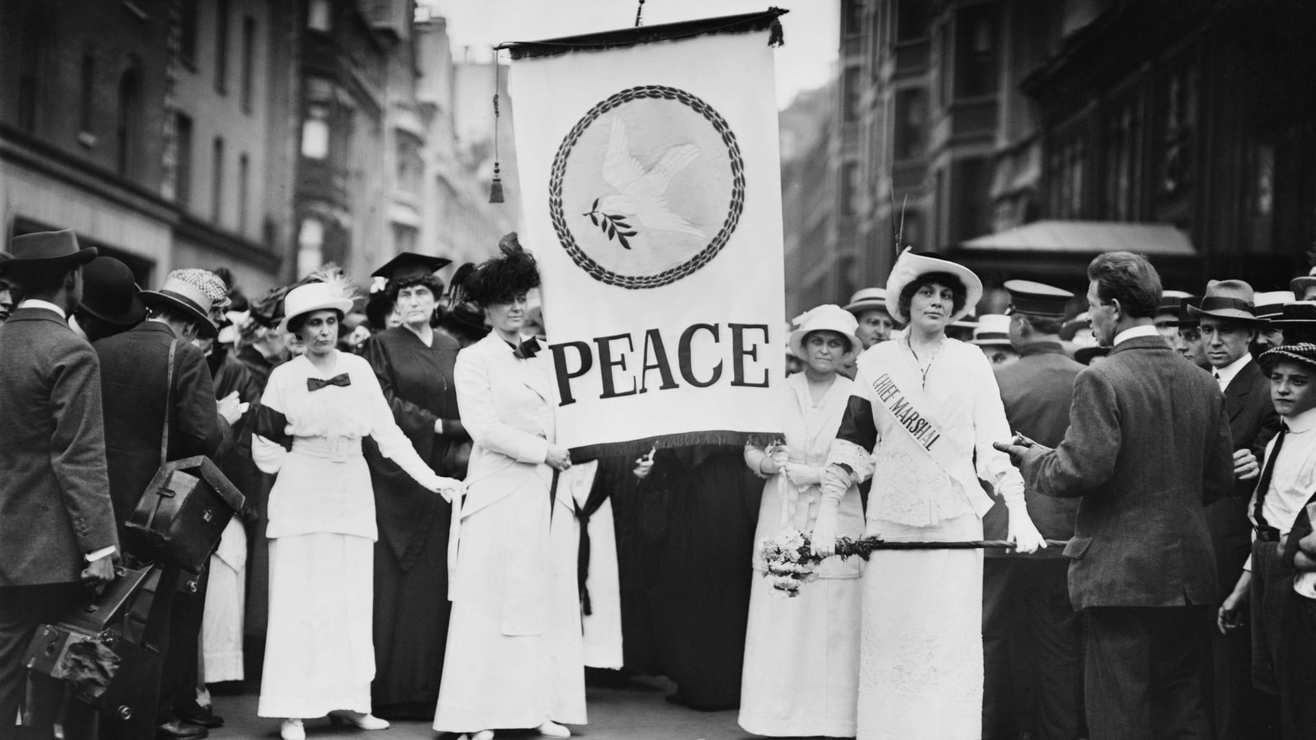 Friedensaktivistinnen protestieren Ende August 1914 in New York gegen den Ersten Weltkrieg. Frauen halten ein Banner mit der Aufschrift „Peace“ – „Frieden“ in der Hand. Friedensaktivistinnen protestieren Ende August 1914 in New York gegen den Ersten Weltkrieg. Frauen halten ein Banner mit der Aufschrift „Peace“ – „Frieden“ in der Hand.