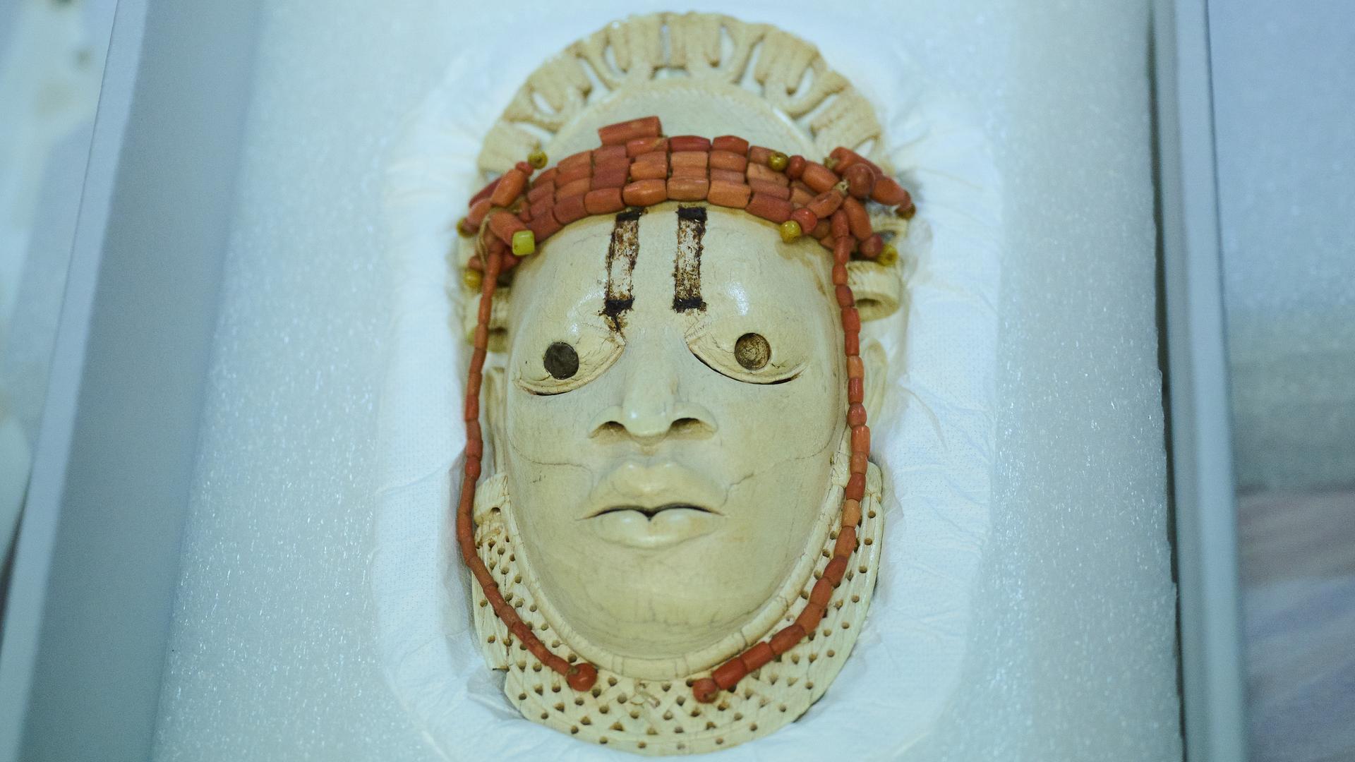 Eine Miniaturmaske aus Elfenbein in einer Vitrine. Eine Miniaturmaske aus Elfenbein in einer Vitrine.