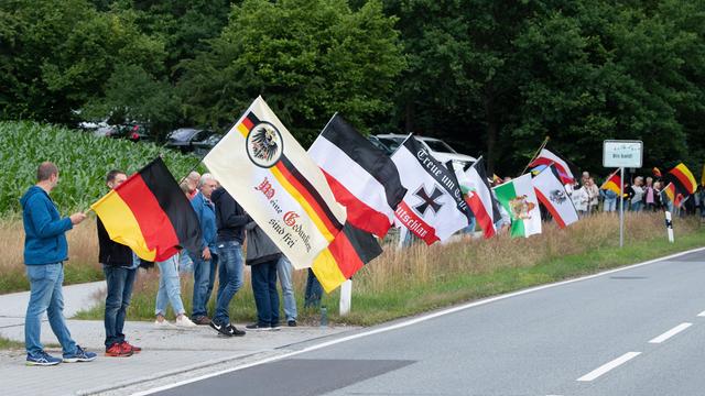 Teilnehmer eines Protests stehen mit Fahnen an der Bundesstraße 96 in Sachsen. Die sogenannten B 96-Proteste richten sich unter anderem gegen die vermeintliche Überregulierung des Staates in Coronazeiten.