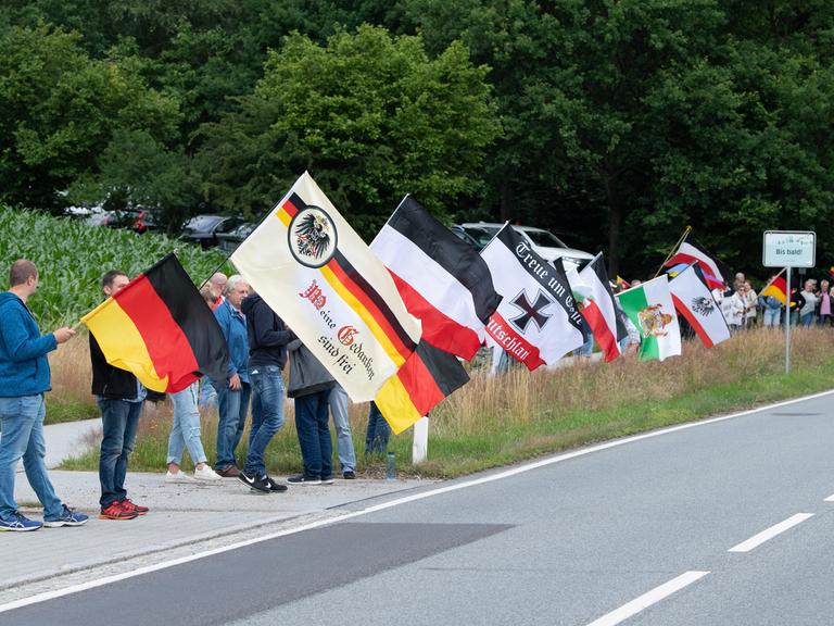 Teilnehmer eines Protests stehen mit Fahnen an der Bundesstraße 96 in Sachsen. Die sogenannten B 96-Proteste richten sich unter anderem gegen die vermeintliche Überregulierung des Staates in Coronazeiten.