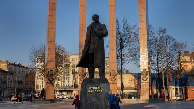 Kinder laufen um eine Statue von Stepan Bandera in Lviv herum.