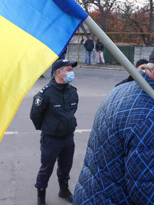 Ein älterer Mann mit der Flagge Moldaus, im Hintergrund steht ein Polizist.