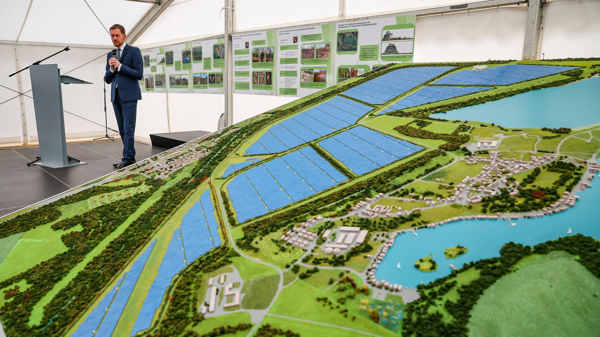 Ein Mann steht neben einem Modell eines Solarparks. Ein Mann steht neben einem Modell eines Solarparks.