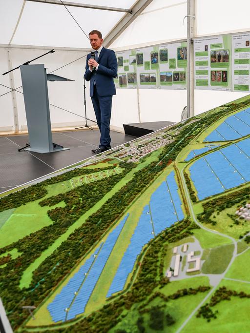Ein Mann steht neben einem Modell eines Solarparks.