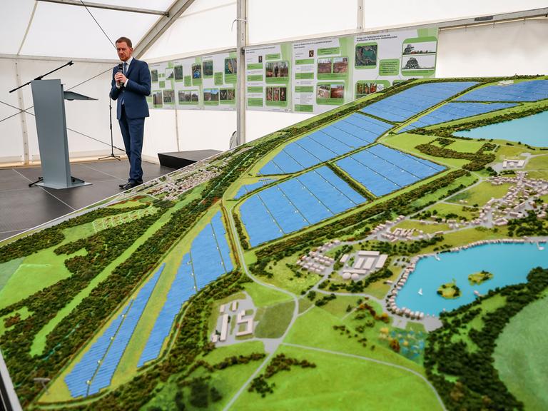 Ein Mann steht neben einem Modell eines Solarparks.