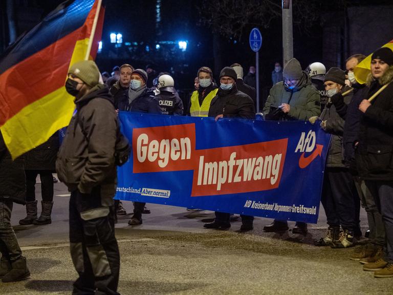 Mitglieder und Sympathisanten der Partei Alternative für Deutschland (AfD) demonstrieren in Greifswald gegen die Corona-Maßnahmen und tragen dabei ein Transparent mit der Aufschrift "Gegen Impfzwang AfD".