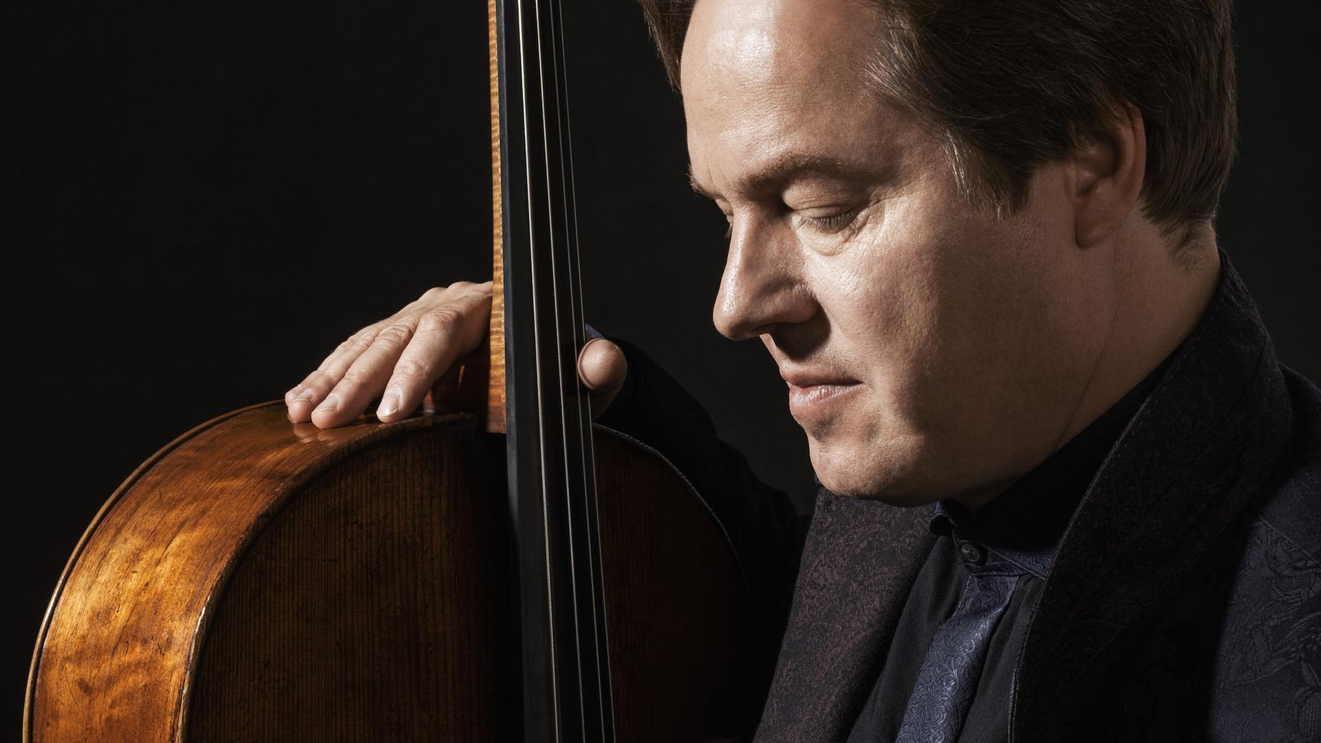 Jan Vogler hat seine Hand auf das Violoncello gelegt und schaut gedankenversunken auf die Saiten. Jan Vogler hat seine Hand auf das Violoncello gelegt und schaut gedankenversunken auf die Saiten.