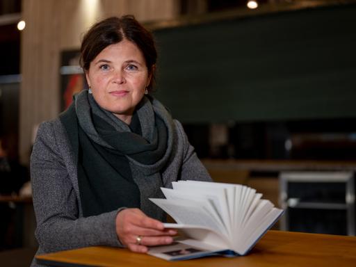 Schriftstellerin Julia Franck sitzt an einem Tisch mit einem aufgeschlagenen 