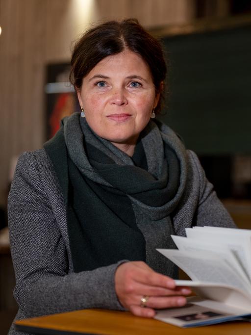 Schriftstellerin Julia Franck sitzt an einem Tisch mit einem aufgeschlagenen 