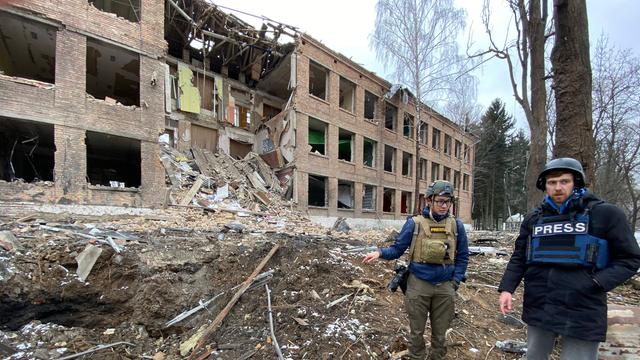 Zwei Journalisten stehen im ukrainischen Wassylkiw (bei Kiew) vor einem zerstörten Gebäude - eine Agenturaufnahme
