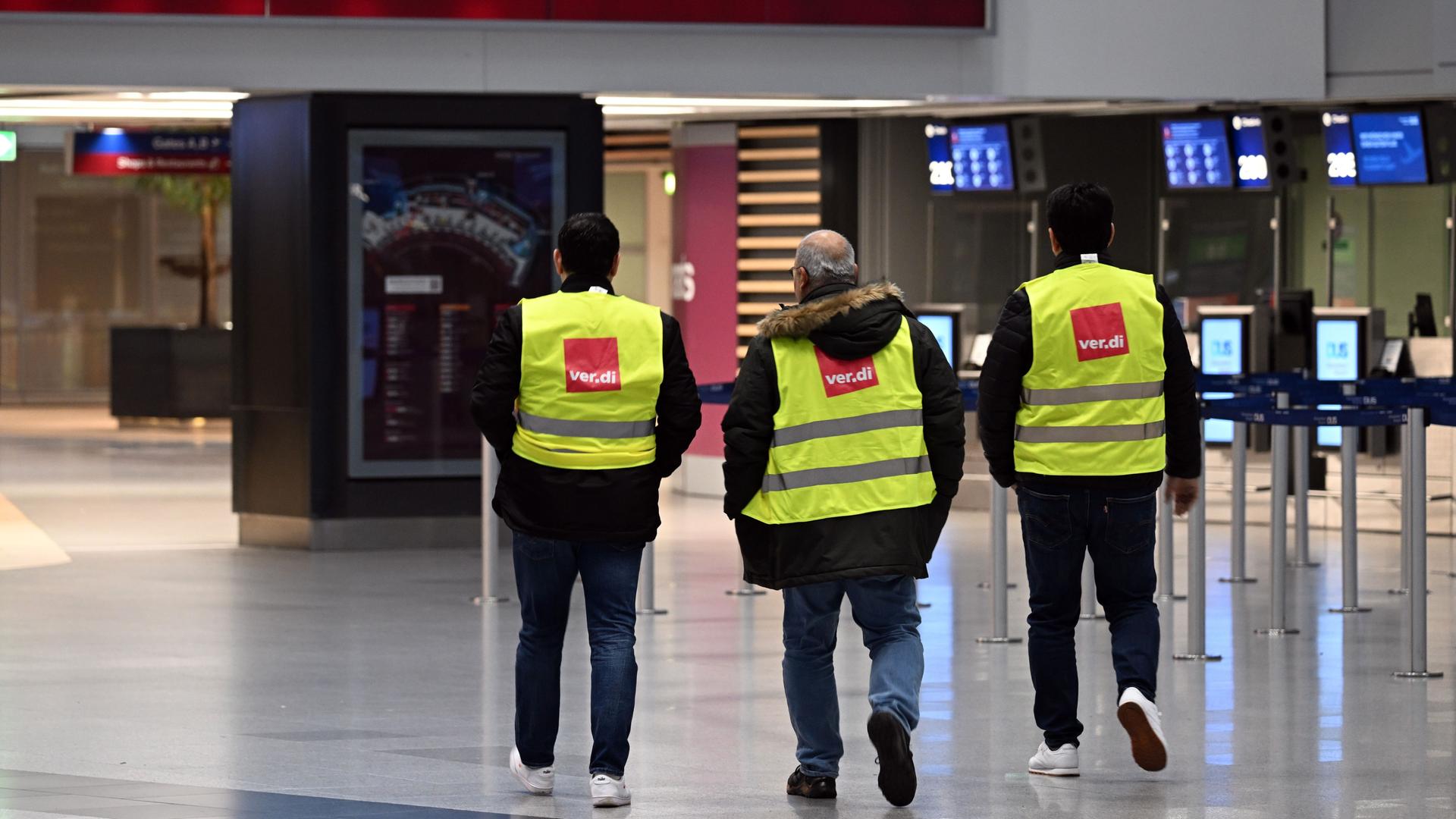 Nordrhein-Westfalen, Düsseldorf: Männer in Verdi-Westen gehen durch den Flughafen in Düsseldorf. Die Gewerkschaft Verdi hat ihre Mitglieder zu Warnstreiks an den nordrhein-westfälischen Flughäfen und im öffentlichen Dienst aufgerufen. Nordrhein-Westfalen, Düsseldorf: Männer in Verdi-Westen gehen durch den Flughafen in Düsseldorf. Die Gewerkschaft Verdi hat ihre Mitglieder zu Warnstreiks an den nordrhein-westfälischen Flughäfen und im öffentlichen Dienst aufgerufen.