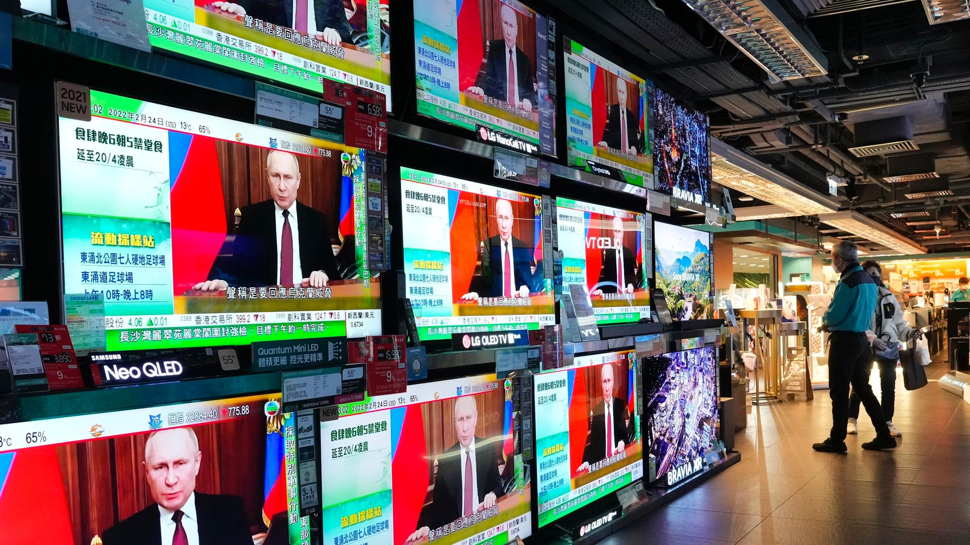 Menschen in Hongkong schauen auf mehrere Fernsehbildschirme, auf denen Putin zu sehen ist. Menschen in Hongkong schauen auf mehrere Fernsehbildschirme, auf denen Putin zu sehen ist.