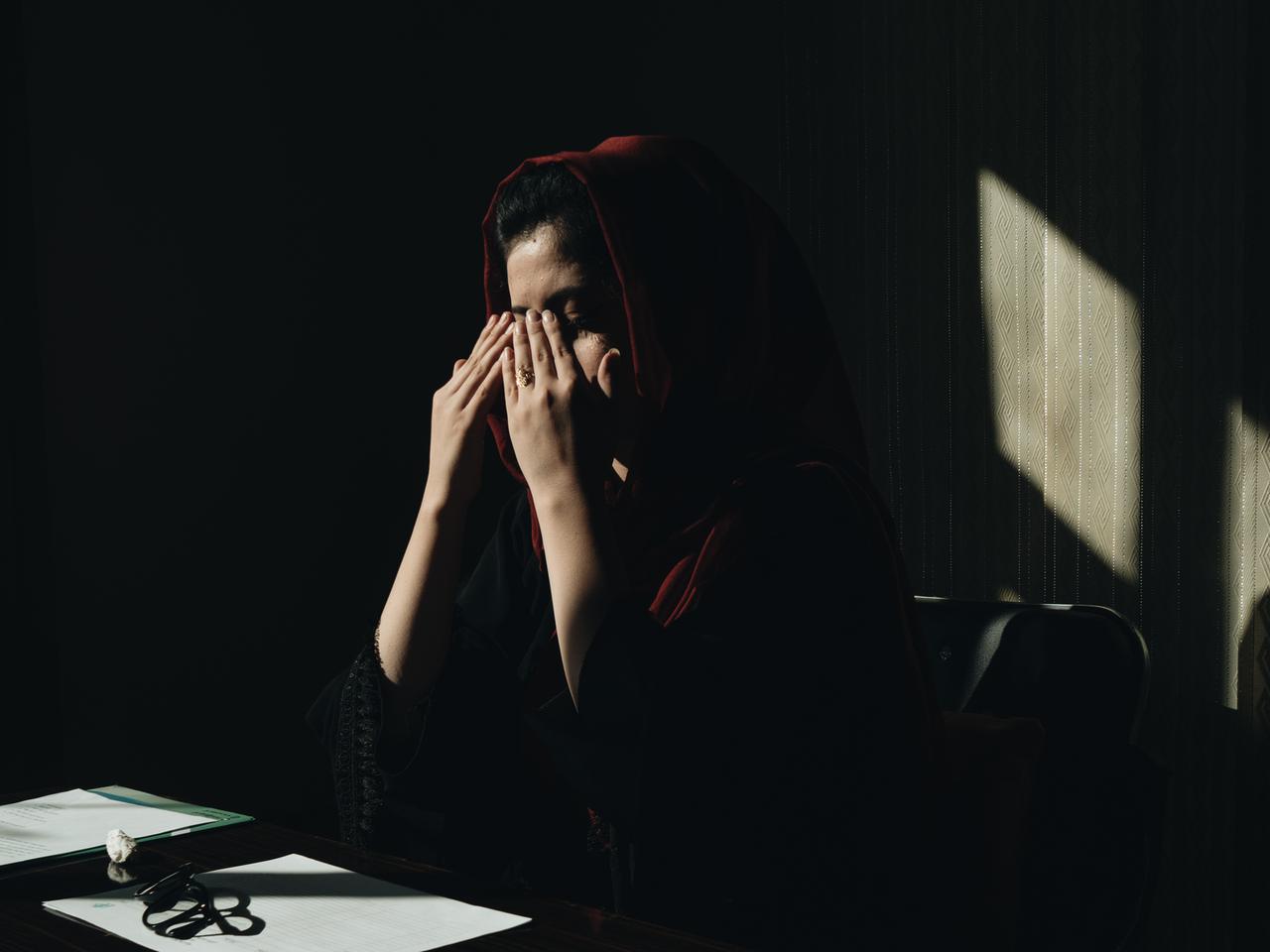 Eine afghanische Frau mit Kopftuch hält sich die Hände vor das Gesicht. Eine afghanische Frau mit Kopftuch hält sich die Hände vor das Gesicht.