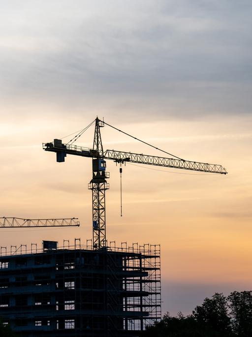 Baustelle bei Sonnenaufgang mit zwei Kränen.