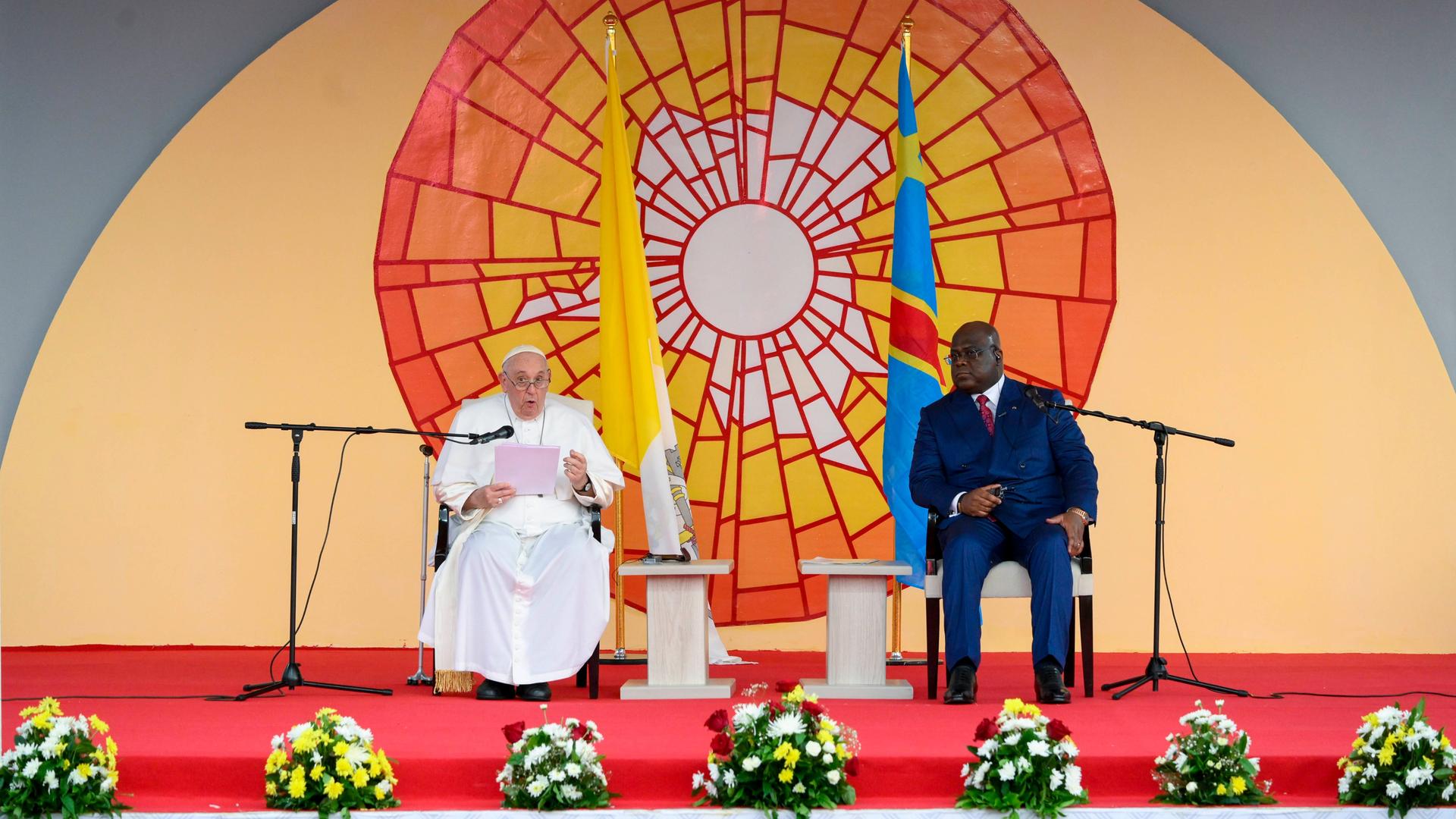 Papst Franziskus sitzt neben dem Präsidenten der Demokratischen Republik Kongo, Felix Tshiseke vor einem bunten Sonnenbild. Papst Franziskus sitzt neben dem Präsidenten der Demokratischen Republik Kongo, Felix Tshiseke vor einem bunten Sonnenbild.
