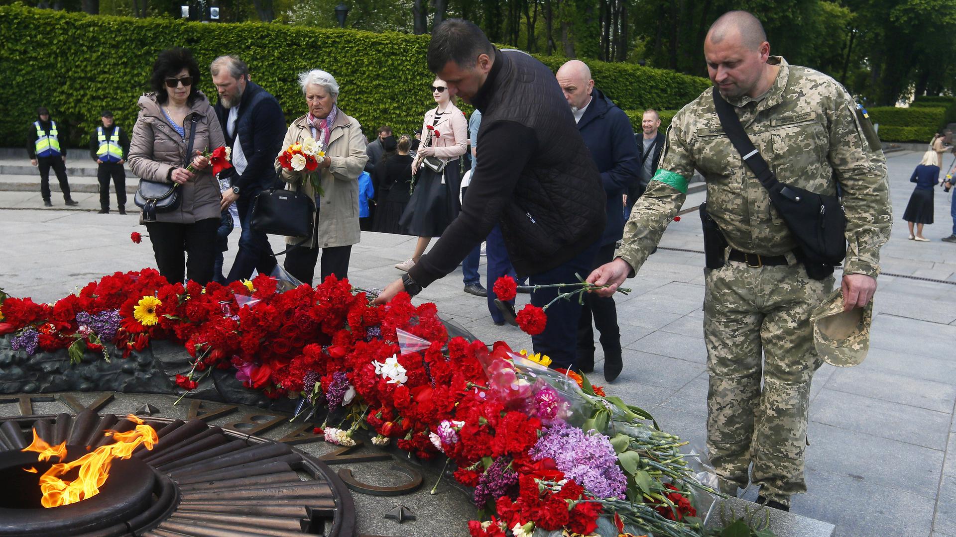 Das Foto zeigt einen Soldaten in Kiew, der am Grab des Unbekannten Soldaten Blumen niederlegt.