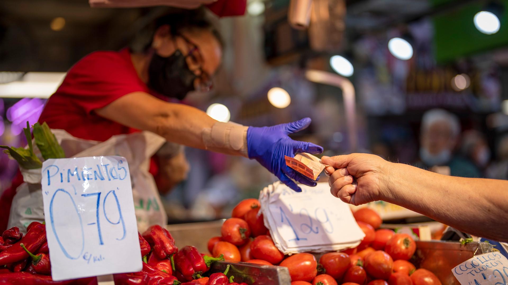 Ein Kunde zahlt für Gemüse auf einem Markt in der spanischen Hauptstadt Madrid
