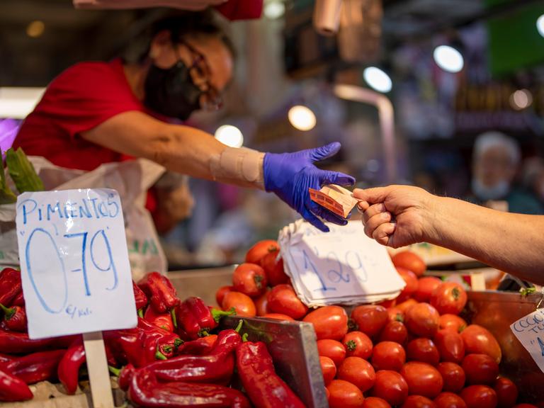 Ein Kunde zahlt für Gemüse auf einem Markt in der spanischen Hauptstadt Madrid
