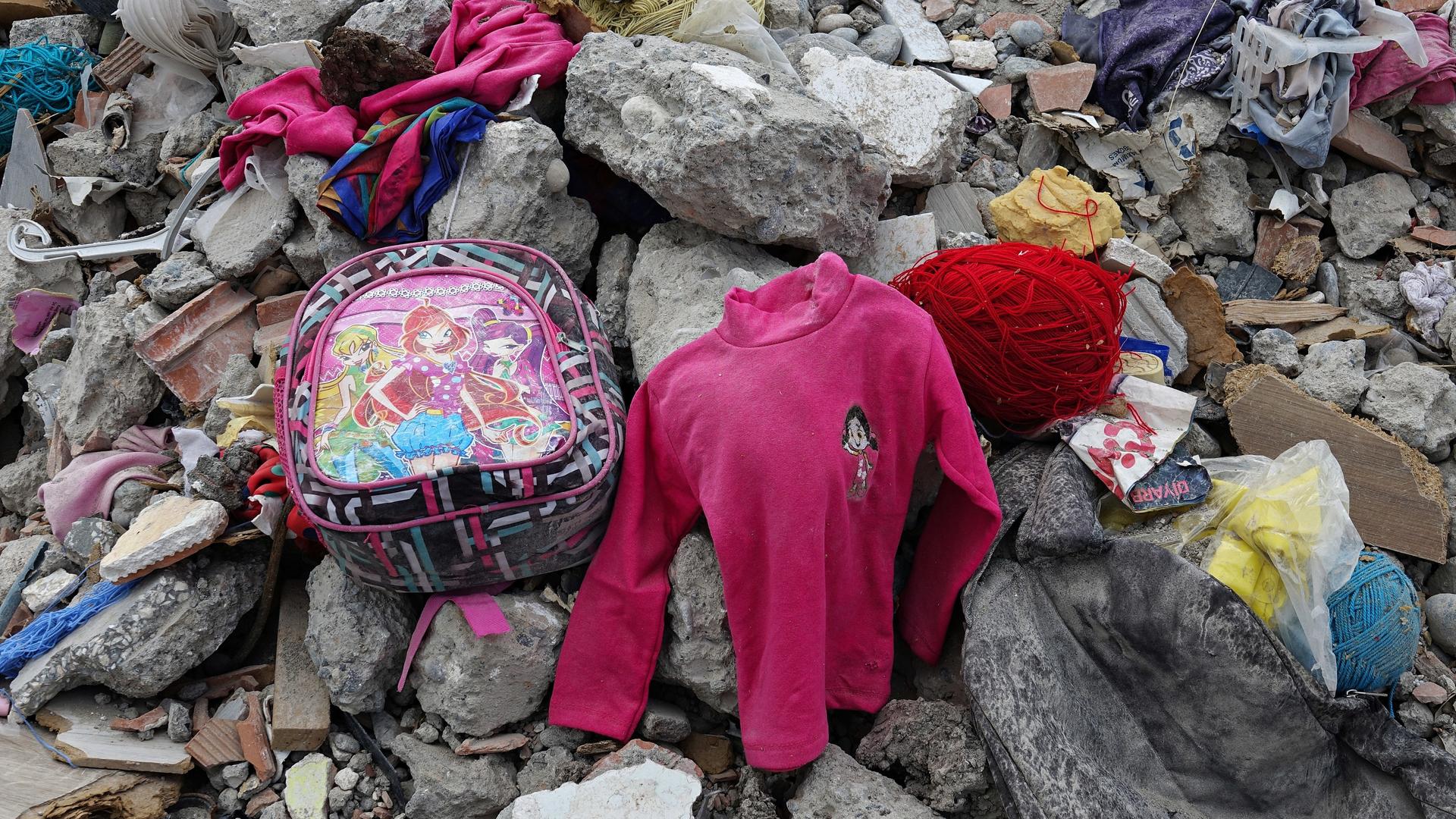 Zwischen den Trümmern eines zerstörten Hauses liegen nach dem Erdbeben in der Türkei Kinderkleidung und ein Rucksack herum. 
