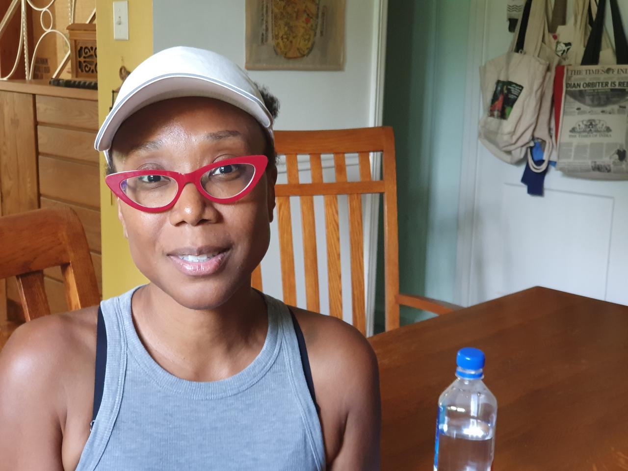Juanita Miller ist in einer Küche, trägt ein weißes Basecap und eine rote Brille. Juanita Miller ist in einer Küche, trägt ein weißes Basecap und eine rote Brille.