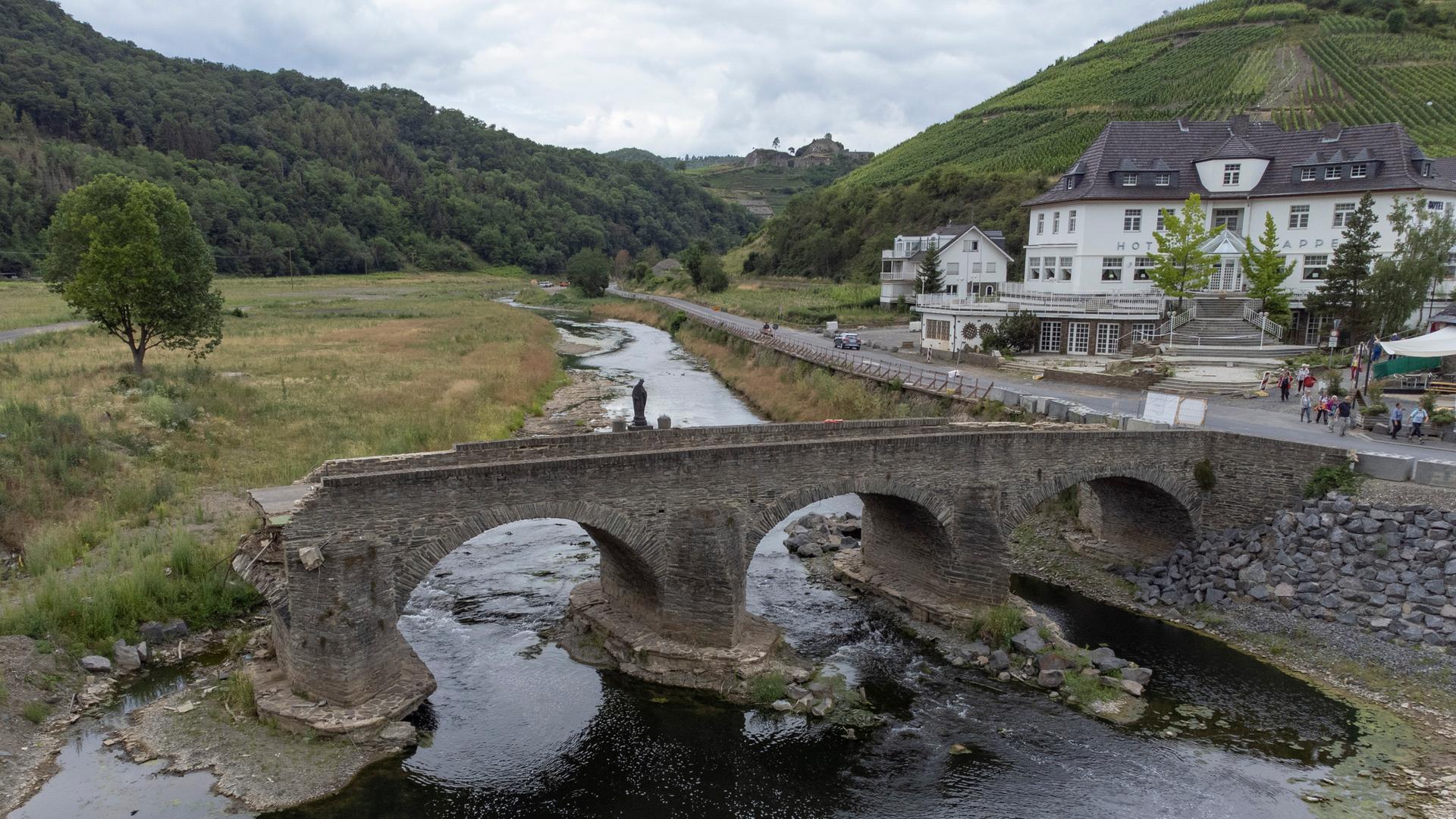 Die bei der Flut im Sommer 2021 zerstörte historische Bogenbrücke in Rech ragt in die Ahr hinein. Die bei der Flut im Sommer 2021 zerstörte historische Bogenbrücke in Rech ragt in die Ahr hinein.