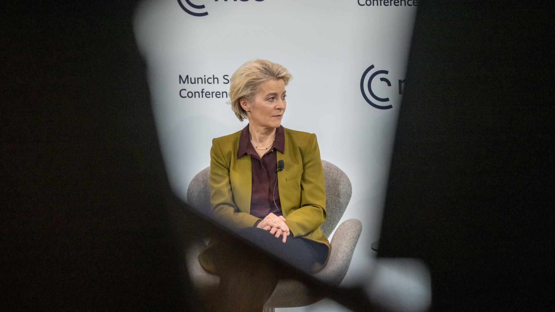 Ursula von der Leyen, Präsidentin der Europäischen Kommission, während der Münchner Sicherheitskonferenz. Sie schaut nachdenklich zur Seite, ihr Konterfei ist eingerahmt von dunklen Rändern. Der Fotograf hat offenbar zwischen anderen Menschen hindurch fotografiert. 