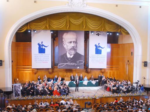 Die Bühne mit Teilnehmern des Internationalen Tschaikowsky-Wettbewerbs in Moskau, darüber ein großen Plakat mit dem Bild von Tschaikowsky 
