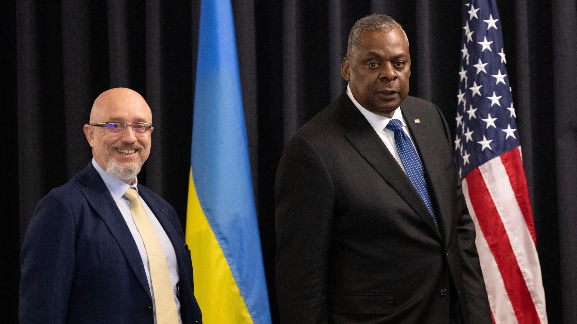 Die Verteidigungs-Minister von der Ukraine und von den USA stehen neben ihren Landes-Flaggen. Die Verteidigungs-Minister von der Ukraine und von den USA stehen neben ihren Landes-Flaggen.