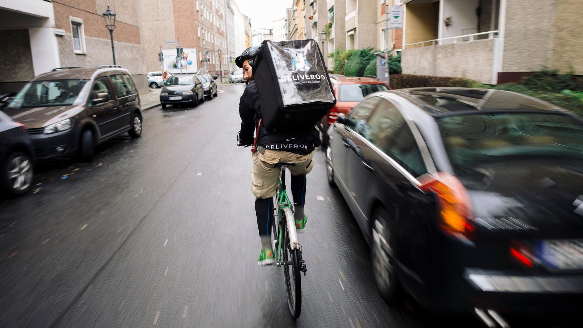 Ein Fahrradkurier des Lieferdienstes "Deliveroo" fährt mit seinem Fahrrad durch den Stadtverkehr in Berlin. 