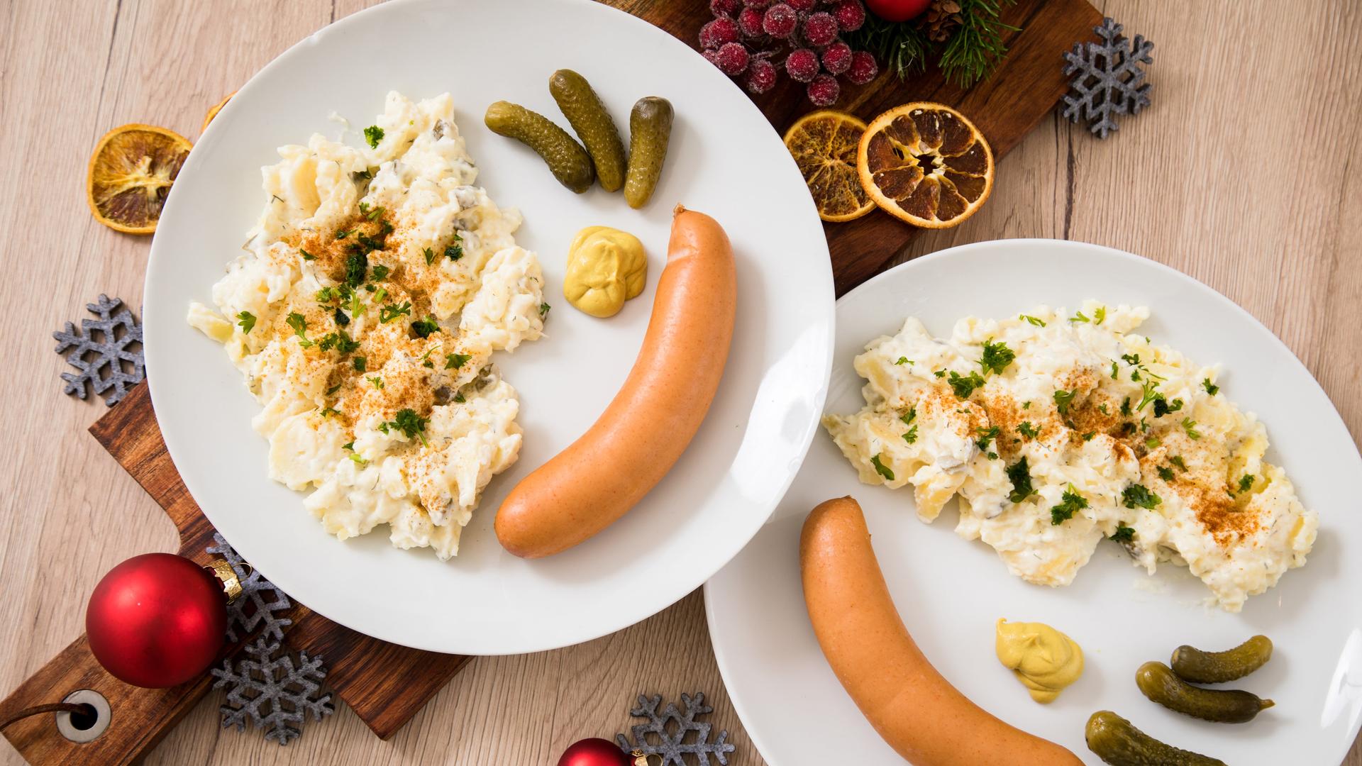 Kartoffelsalat mit Würstchen sind auf Tellern angerichtet (gestellte Szene) Kartoffelsalat mit Würstchen sind auf Tellern angerichtet (gestellte Szene)