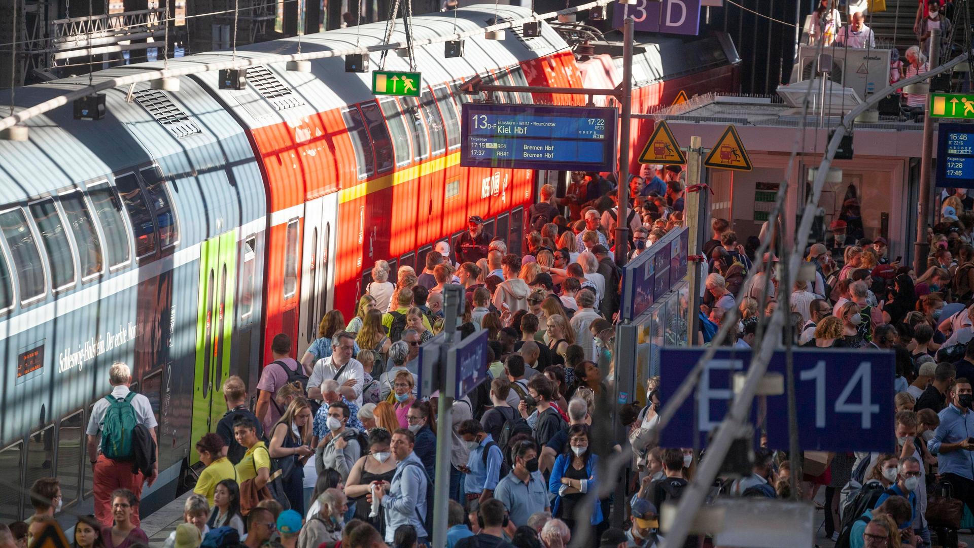 Sehr viele Menschen stehen auf einem Bahnsteig neben einem Doppelstockzug. Sehr viele Menschen stehen auf einem Bahnsteig neben einem Doppelstockzug.