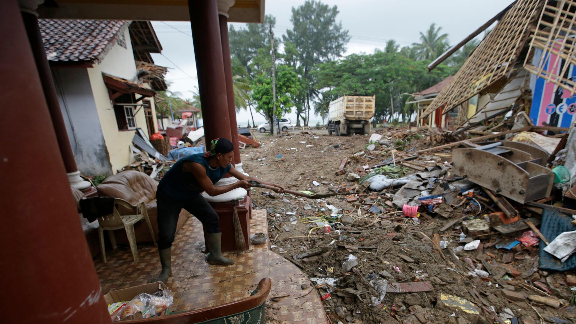 Nach einem Tsunami im Dezember 2018 versucht ein Mann in der indonesischen Region Carita sein Haus und Grundstück aufzuräumen Nach einem Tsunami im Dezember 2018 versucht ein Mann in der indonesischen Region Carita sein Haus und Grundstück aufzuräumen