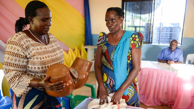 Zwei Frauen mit einem Model einer Vulva an dem die Grausamkeit der Genitalverstümmelung nachvollzogen werden kann.