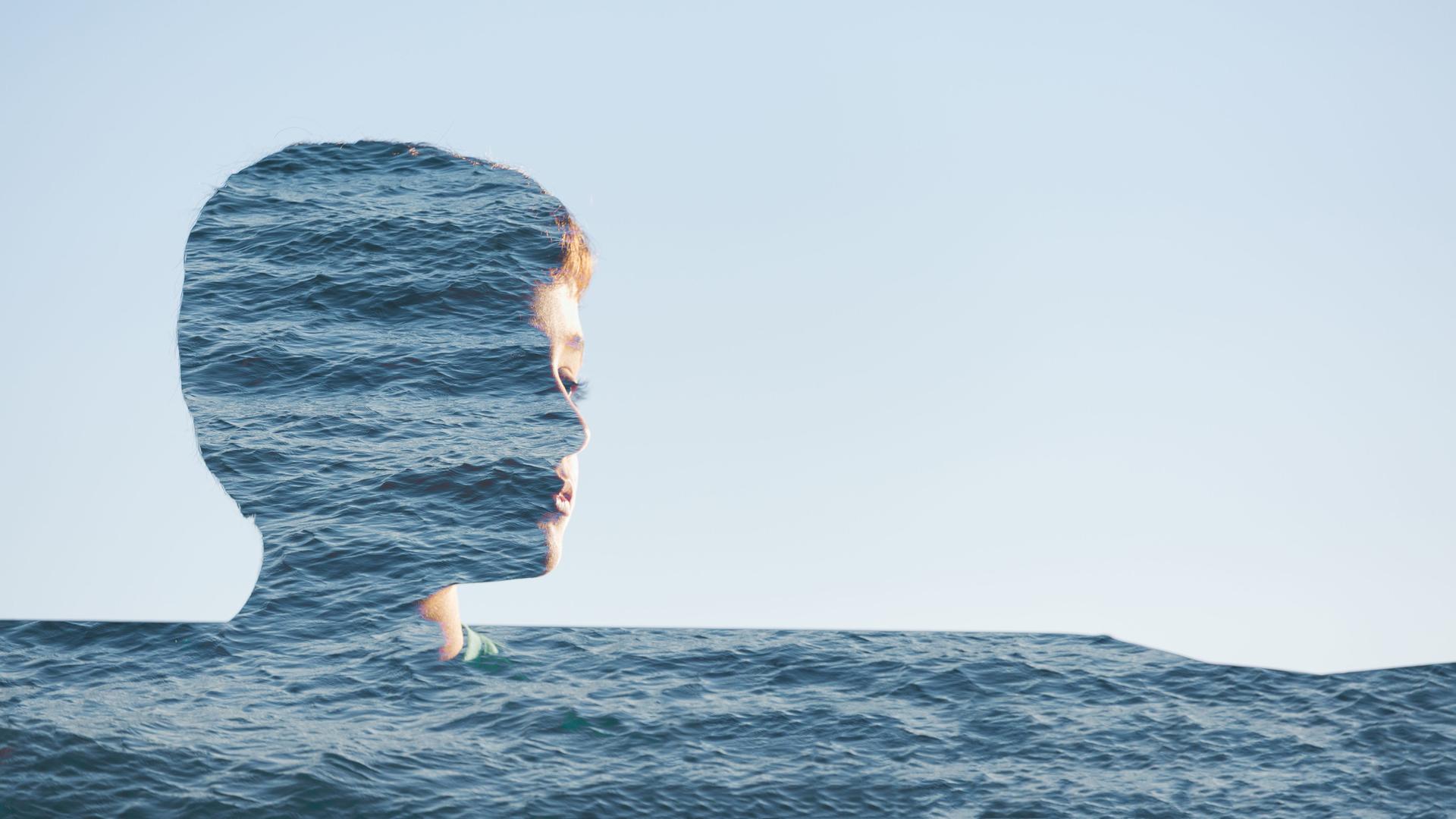 Fotomontage eines Jungenportraits, das scheinbar im Meer untergeht Fotomontage eines Jungenportraits, das scheinbar im Meer untergeht
