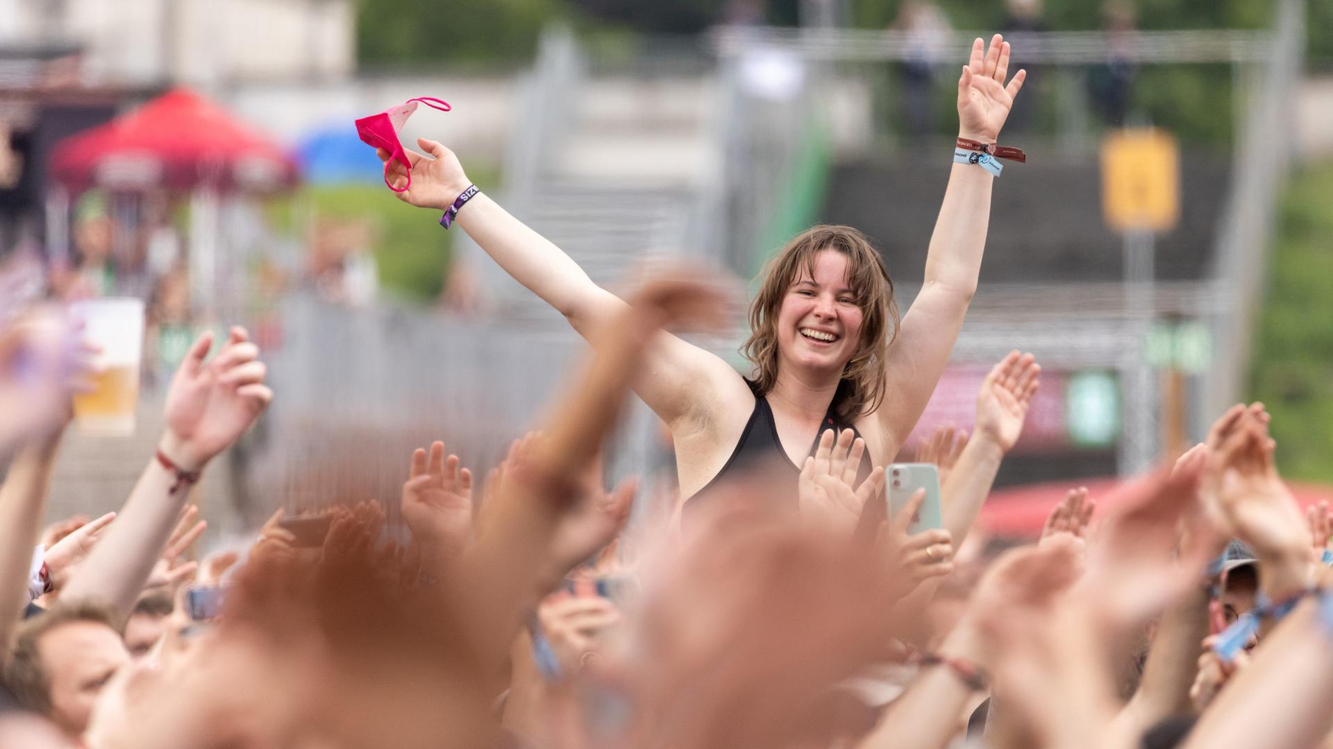 Eine Besucherin singt beim Open-Air-Festival "Rock im Park" während eines Konzerts auf den Schultern eines Person sitzend. Eine Besucherin singt beim Open-Air-Festival "Rock im Park" während eines Konzerts auf den Schultern eines Person sitzend.