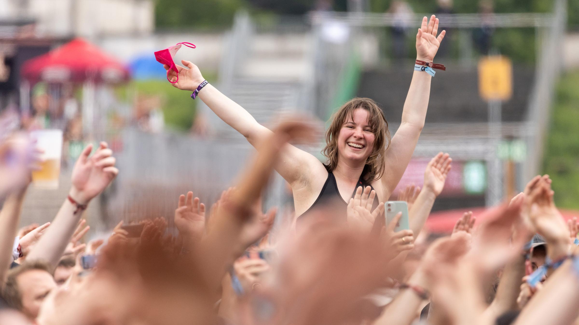 Eine Besucherin singt beim Open-Air-Festival "Rock im Park" während eines Konzerts auf den Schultern eines Person sitzend. Eine Besucherin singt beim Open-Air-Festival "Rock im Park" während eines Konzerts auf den Schultern eines Person sitzend.