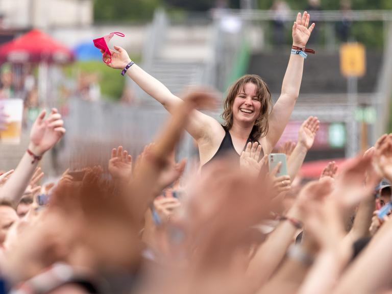 Eine Besucherin singt beim Open-Air-Festival "Rock im Park" während eines Konzerts auf den Schultern eines Person sitzend. 