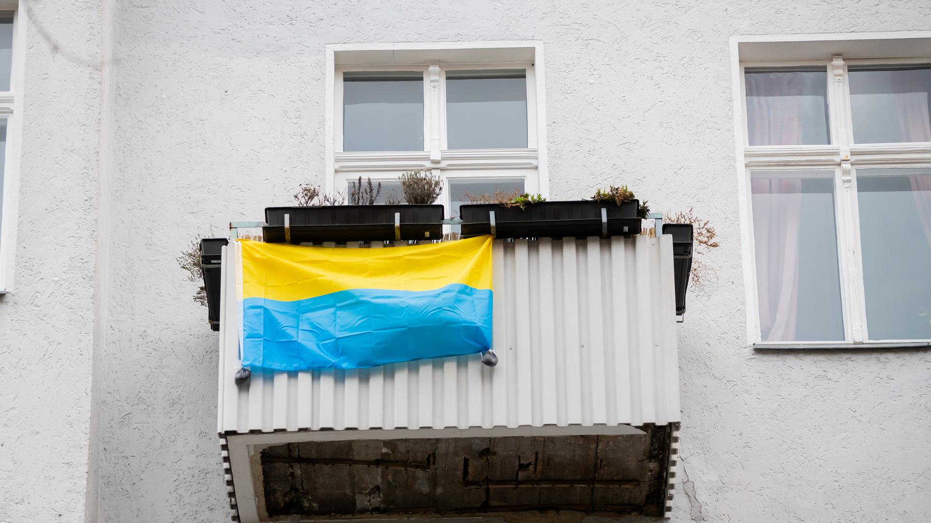 Ein Bild aus dem Frühjahr 2022: Eine ukrainische Flagge hängt in Solidarität mit der Ukraine an einem Balkon im Berliner Ortsteil Schöneberg.