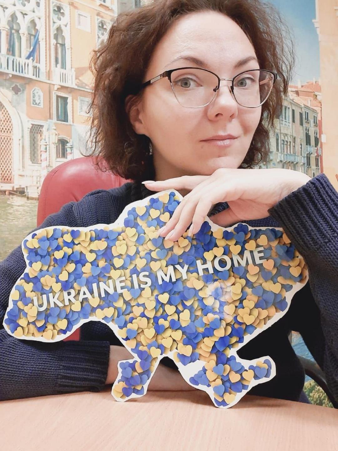 Eine Frau mit roten Haaren hält ein Schild mit der Aufschrift "Ukraine is my home". Eine Frau mit roten Haaren hält ein Schild mit der Aufschrift "Ukraine is my home".