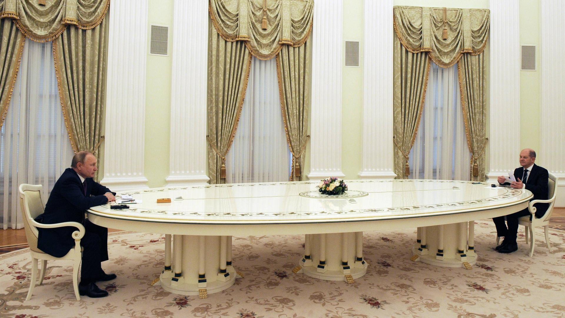 Bundeskanzler Scholz und Russlands Präsident Putin sitzen an einem großen Tisch weit voneinander entfernt.