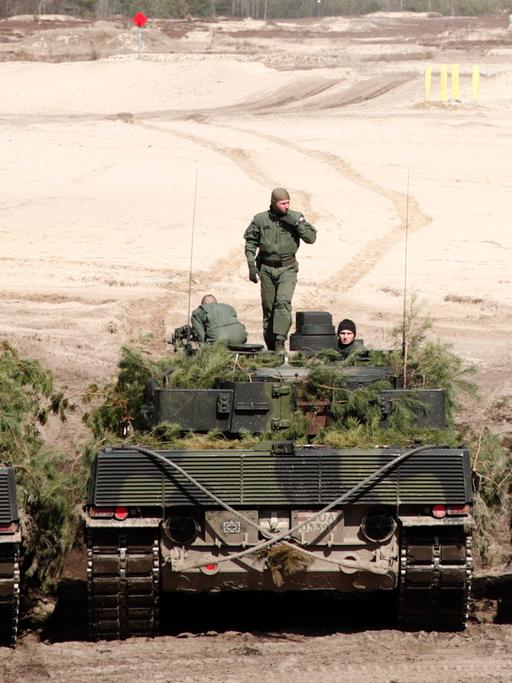 Zwei Leopard-2-Panzer mit jeweils drei Soldaten stehen nebeneinander.
