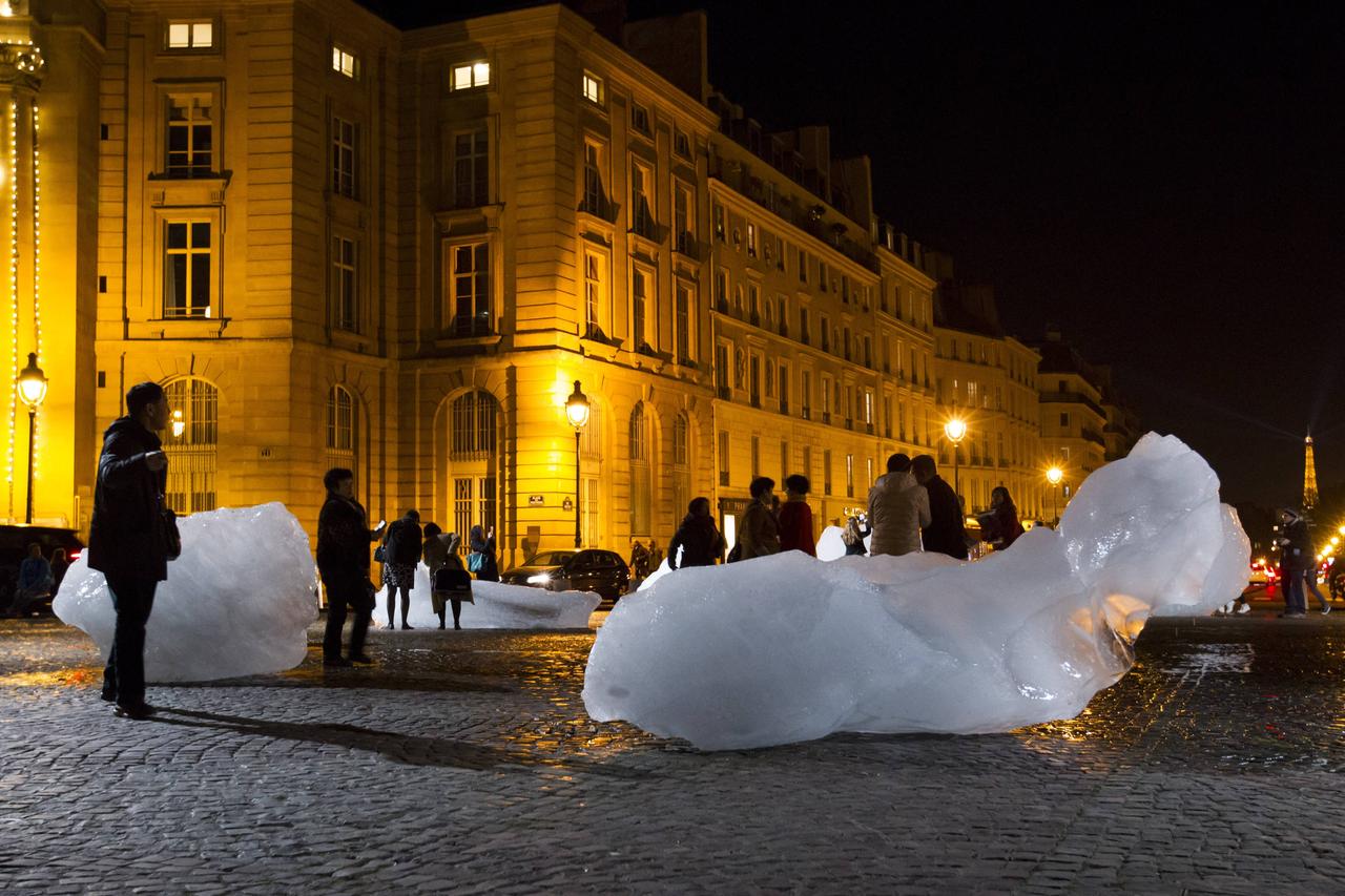 Große Eisblöcke schmelzen im Dunkeln auf einer Straße vor beleuchteten Gebäuden. Große Eisblöcke schmelzen im Dunkeln auf einer Straße vor beleuchteten Gebäuden.