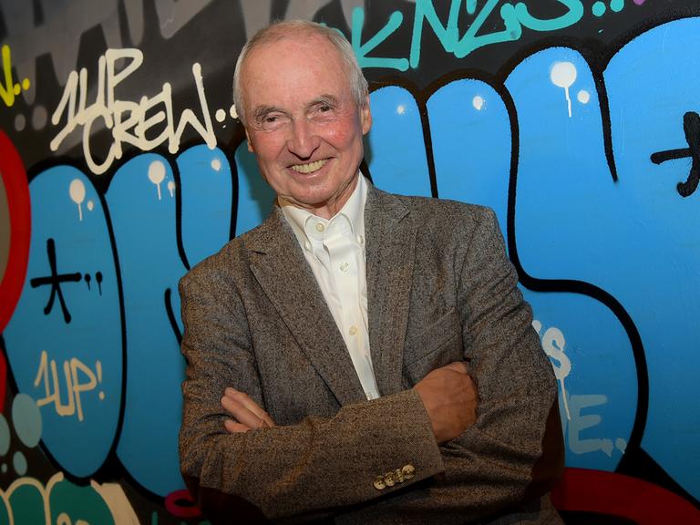 Ein Porträts des Autors und Journalisten Peter Pragal, ersteht vor einer mit Graffiti besprühten Wand im Berliner SO36