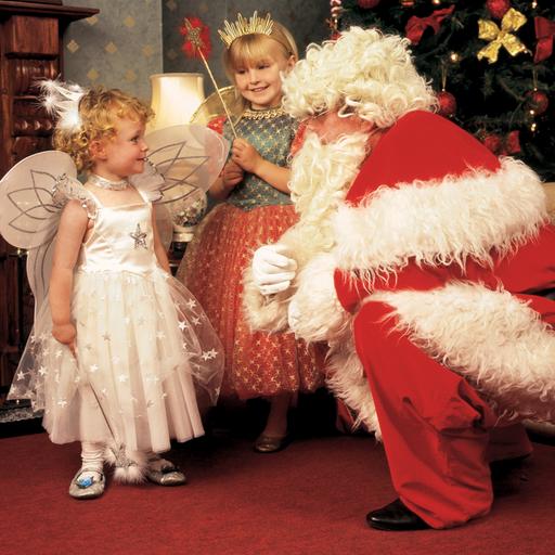 Ein verkleideter Weihnachtsmann und zwei als Christind verkleidete Mädchen in einer gemütlich-rustikalen Umgebung. (Symbolbild)