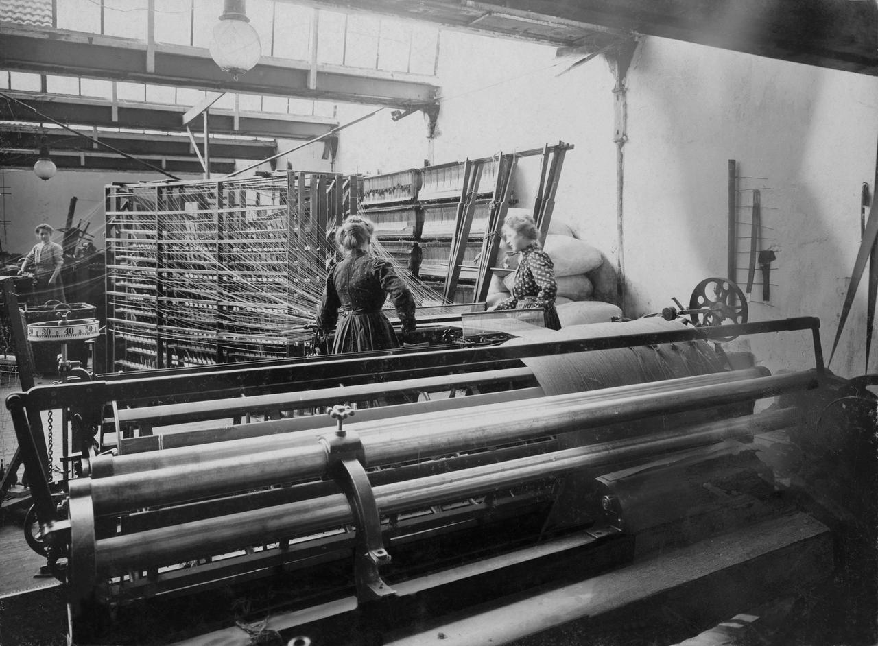 Frauen stehen an einer Maschine, aus der gesponnenes Garn kommt. Um 1910. Frauen stehen an einer Maschine, aus der gesponnenes Garn kommt. Um 1910.