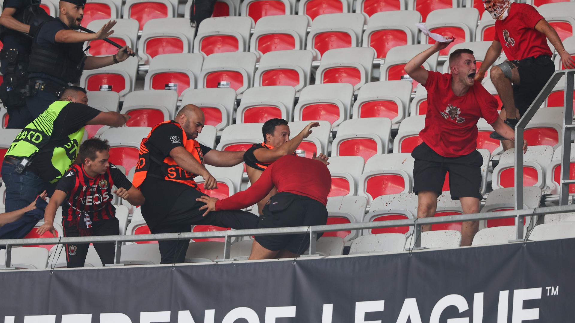 Einer der Stewards tritt einen Kölner Fan, andere Fans und Stewards sowie Polizist rennen auf den Rängen umher. Einer der Stewards tritt einen Kölner Fan, andere Fans und Stewards sowie Polizist rennen auf den Rängen umher.