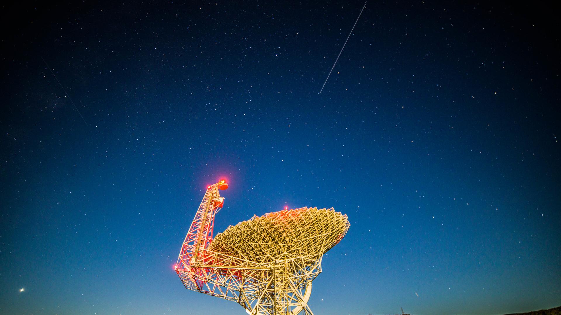 Das Green-Bank-Teleskop in West Virigina bei Nacht - am Himmel zeigt sich eine Satellitenspur.
